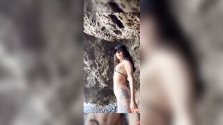 Ragazza in micro bikini tatuata strip in pubblico sugli scogli